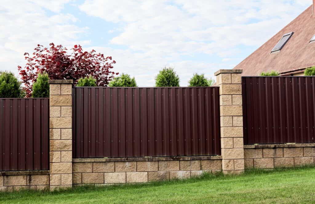 Brown metal profile fence with block posts.