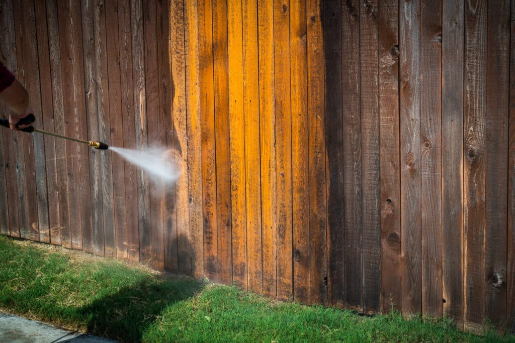 Wooden fence spraying a high Pressure washing a dirty grimy old wooden fence